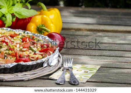 Vegetable tart on rustic wooden table in the garden. Selective focus