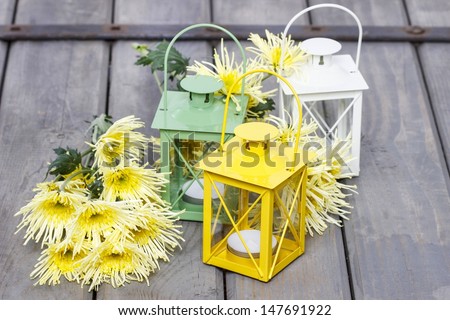 Colorful lanterns and yellow chrysanthemums. Beautiful colorful lanterns on wooden table at summer party.