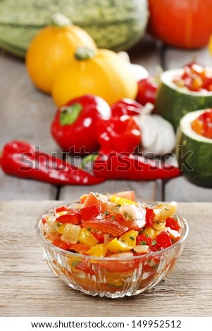 Fresh colorful vegetable salad in transparent glass bowl. Raw vegetables in the background.