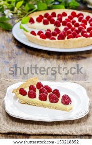 Piece of raspberry tart on wooden table. Summer garden party setting