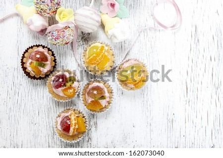 Cupcakes filled with fresh fruits and marshmallows on white wooden background. Great diversity of sweets.
