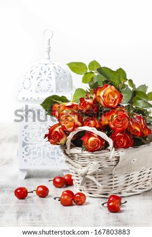 Basket of orange roses and white victorian birdcage on white background