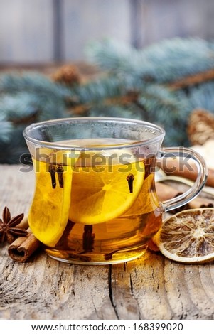 Glass of hot steaming tea among christmas decorations on wooden table