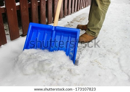 Man removing snow from the sidewalk after snowstorm
