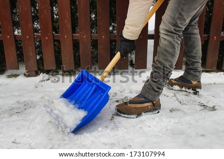 Woman removing snow from the sidewalk after snowstorm