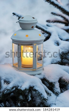 White lantern standing on fir branch in forest. Beautiful winter evening