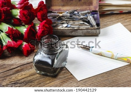 Writing a letter. White sheet of paper, ink and red carnation flowers isolated on wooden background. Copy space.