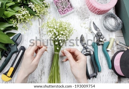 Florist at work. Woman making bouquet of lily of the valley flowers