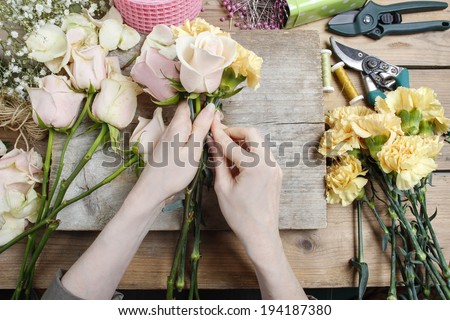 Florist at work. Woman making wedding bouquet of pink roses and yellow carnations
