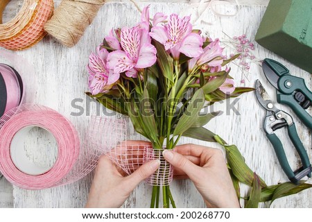 Florist at work: woman arranging bouquet of alstroemeria flowers commonly called the Peruvian lily or lily of the Incas