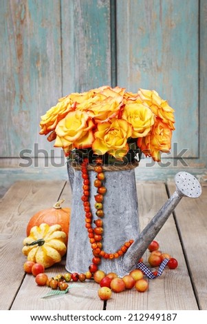 Bouquet of orange roses in silver watering can standing on rustic wooden table