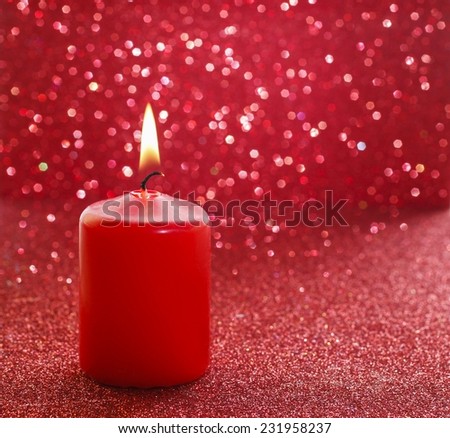 Red candle. Red glittering christmas lights. Blurred abstract background