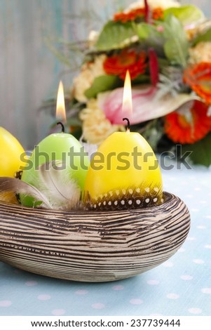 Easter candles in ceramic bowl decorated with quail feathers