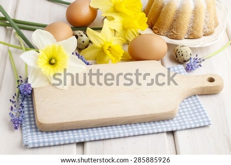 Wooden kitchen board, spring flowers and easter food