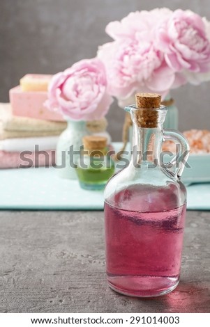 Glass bottle of liquid soap and peonies in the background