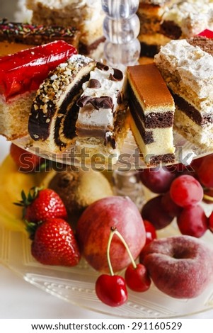Assorted cakes, cookies and fruits on glass cake stand