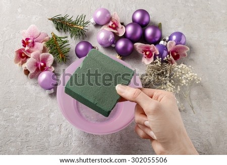 Florist at work: woman making christmas decorations with violet balls, fir and orchid flowers. Step by step, tutorial
