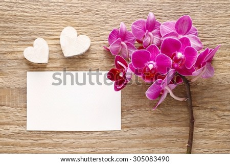 Beautiful pink orchid flowers and sheet of paper (copy space) on wooden background