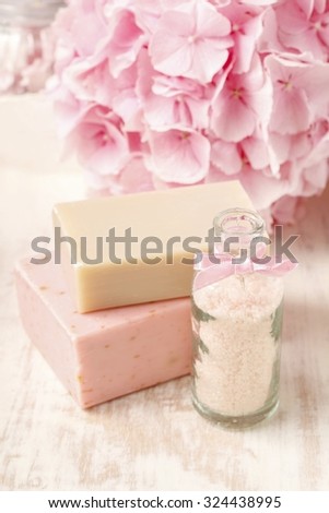 Bottle of sea salt and two bars of handmade soap. Hortensia flower in the background