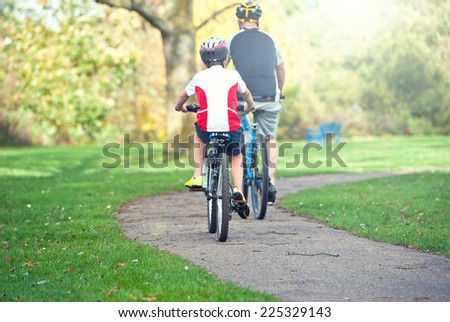 couple ride bicycles in the meadow back to camera