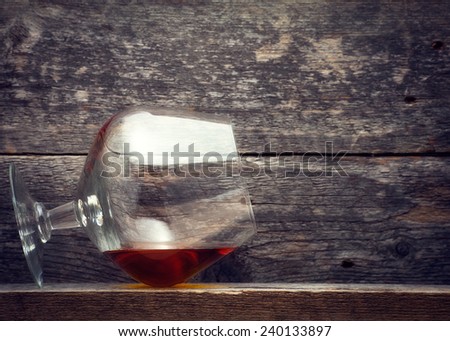 Glowing cognac or brandy in an elegant snifter glass on an old dark wooden bar counter with copyspace