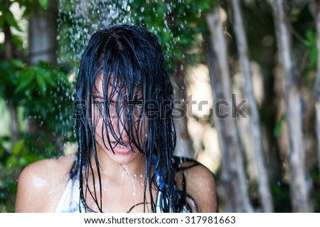 Portrait of beautiful woman enjoying rain at sunny day