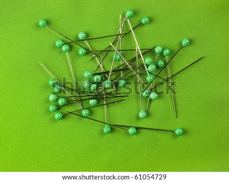 Detail of green sewing pins on green textile background.