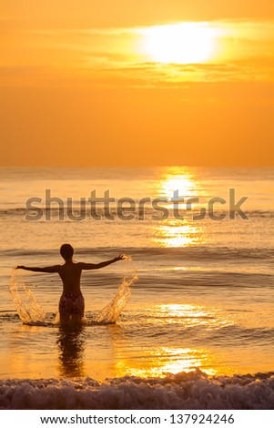 Silhouette of woman that plays with water at the sea