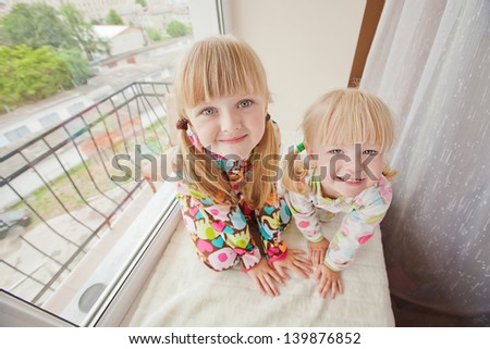 Two girls play at the windows-sill in pyjamas before sleep