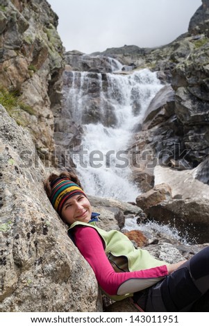 Hiker rests at mountain waterfall in Caucasus mountains in Bezengi region, Kabardino-Balkaria, Russia
