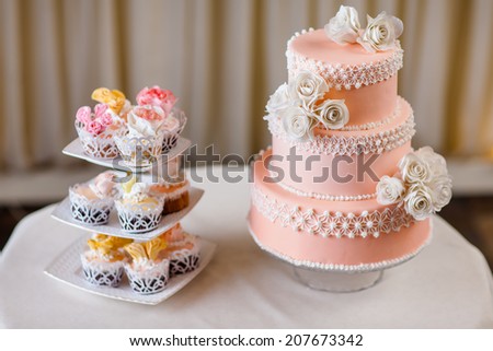 Cupcakes with individual wedding decoration with wedding cake at white table