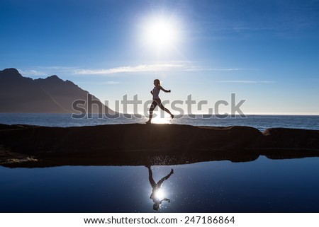 Caucasian woman is jumping against blue ocean in Norway
