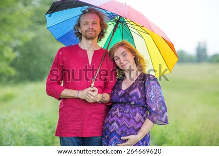 Pregnant couple under an umbrella