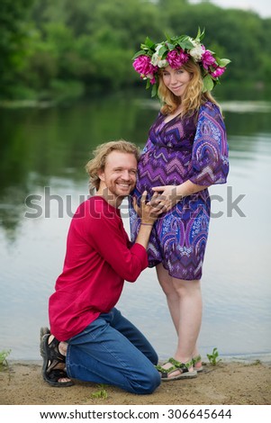 Happy pregnant couple hugging in nature