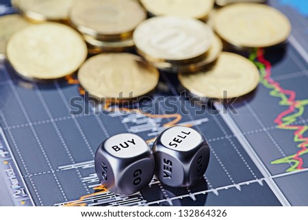 Dices cubes with the words SELL BUY and golden coins on financial chart as the background. Selective focus