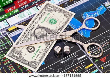 Scissors cutting  one-dollar banknote, dices cubes with the word SELL BUY. Financial charts and columns of prices as background. Selective focus