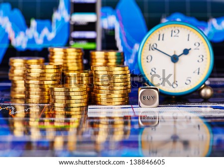 Stacks of golden coins, clock, dices cube with the words BUY. The financial chart as background. Selective focus