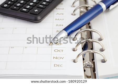 Calculator and ball pen on organizer. Selective focus