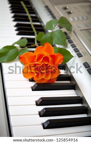 Electronic piano with orange rose flower