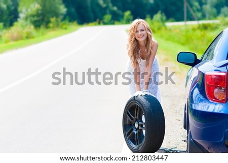 beautiful blond woman near car and wheel tire