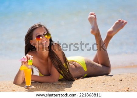 beautiful fun and joy brunette smiling woman in yellow bikini drink orange cocktail in  tropical  blue sea water bali has sports and tan body