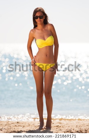 beautiful fun joy sexy smiling brunette lady woman yellow bikini sunglasses  tropical  blue sea water bali has sports and tan body cream adventure  sunscreen close up  sunbathing  leisure amazing