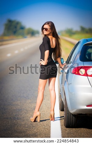 beautiful  brunette  sexy  woman in black dress and sunglasses  has the broken car and  long hair  and elegant body