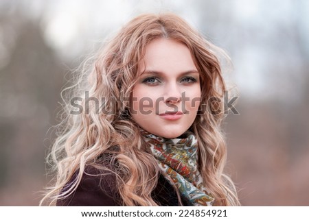 beautiful  blonde  smiling  women  in brown  coat and neckerchief have wonderful  eyes and lips in winter background