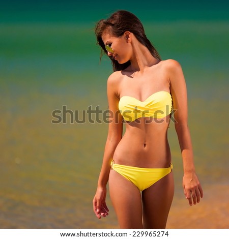 beautiful fun joy sexy smiling brunette lady woman yellow bikini sunglasses tropical blue sea water mauritius sport tan body cream adventure sunscreen close up sunbathing leisure amazing bali