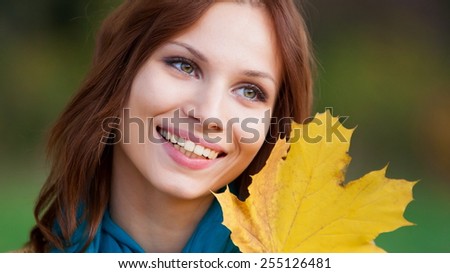 beautiful  fun smiling face  woman with leaves  posing in autumn nature background, has white teeth