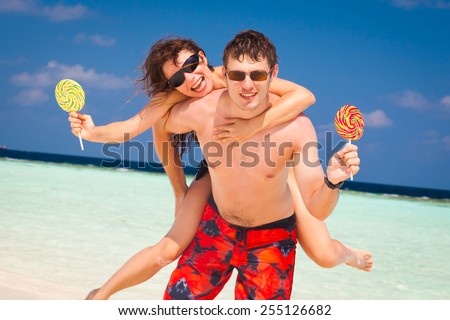 beautiful fun smiling sexy young women  and man with sweet candy lollipop in  romantic  atoll island paradise luxury  resort about coral reef, has sunglasses, honeymoon love