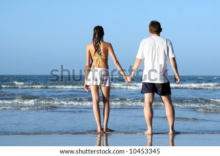 couple hand in hand on the beach by sunset