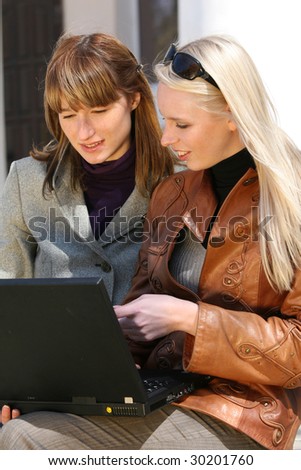 two women working with laptop outdoor