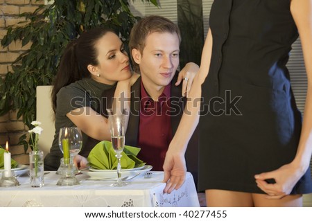 man with girlfriend looking at another woman in restaurant